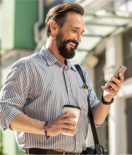 person smiling holding coffee and phone